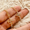 Eine Hand präsentiert eine goldfarbene Zirkonkette und Ohrringe-Set vor einem flauschigen weißen Hintergrund.