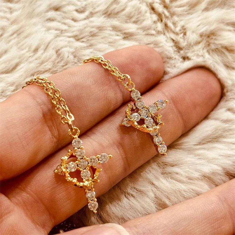 Eine Hand präsentiert eine goldfarbene Zirkonkette und Ohrringe-Set vor einem flauschigen weißen Hintergrund.