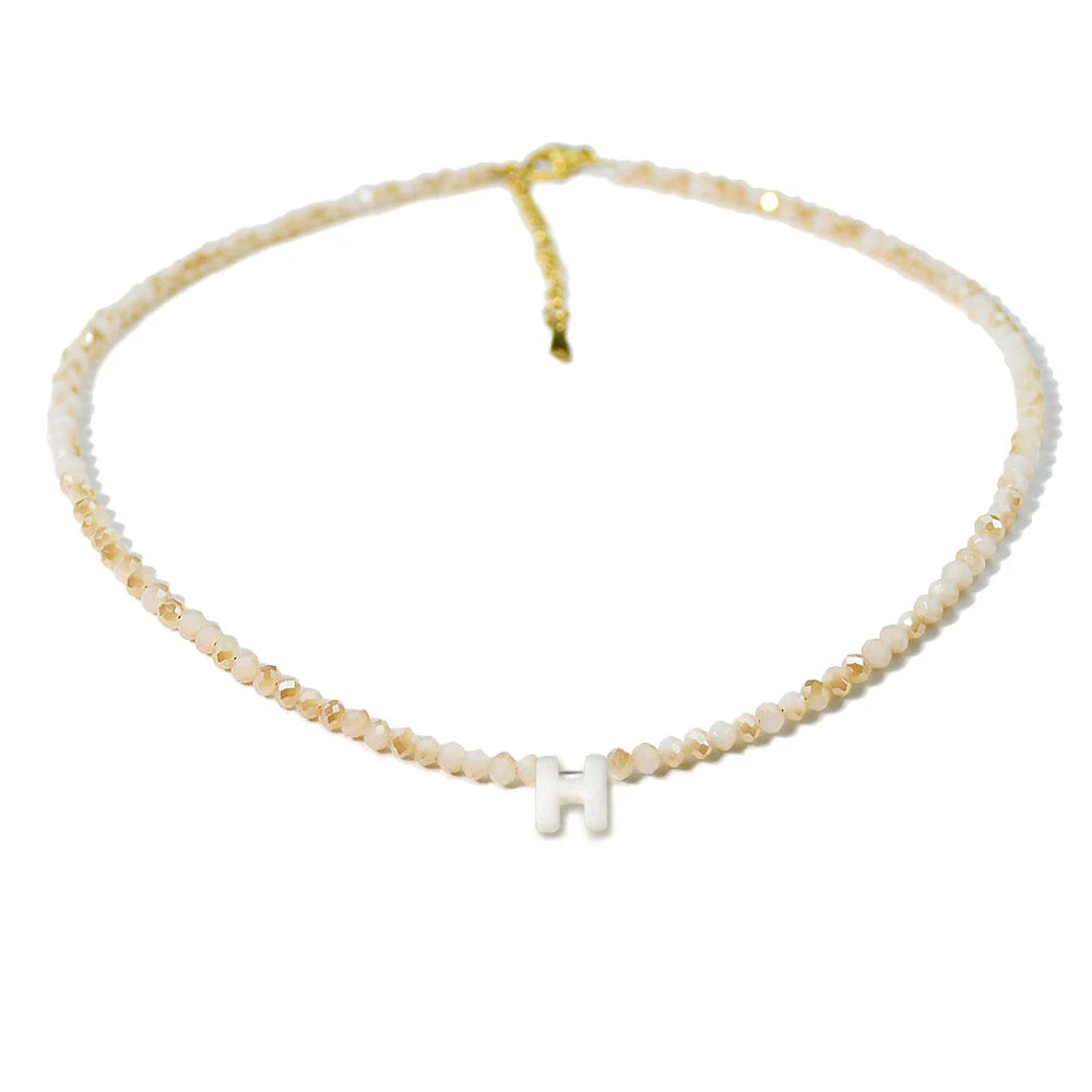 A delicate mother of pearl necklace with crystal accents featuring an initial charm.