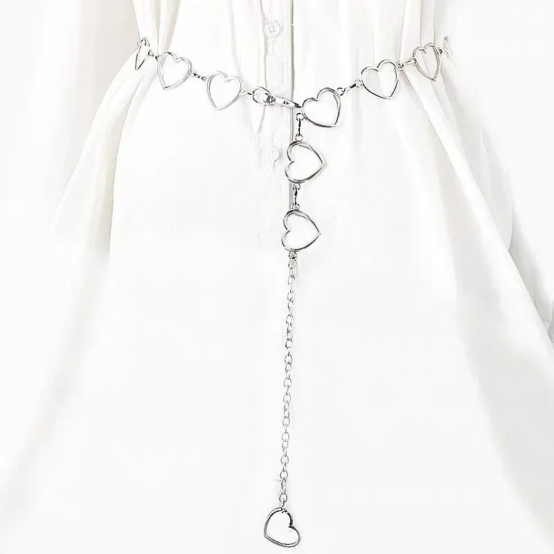 A delicate silver diamond heart chain waist belt displayed against a white fabric background.