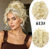A blonde woman shows off a voluminous curly messy bun hairstyle with a hair accessory.