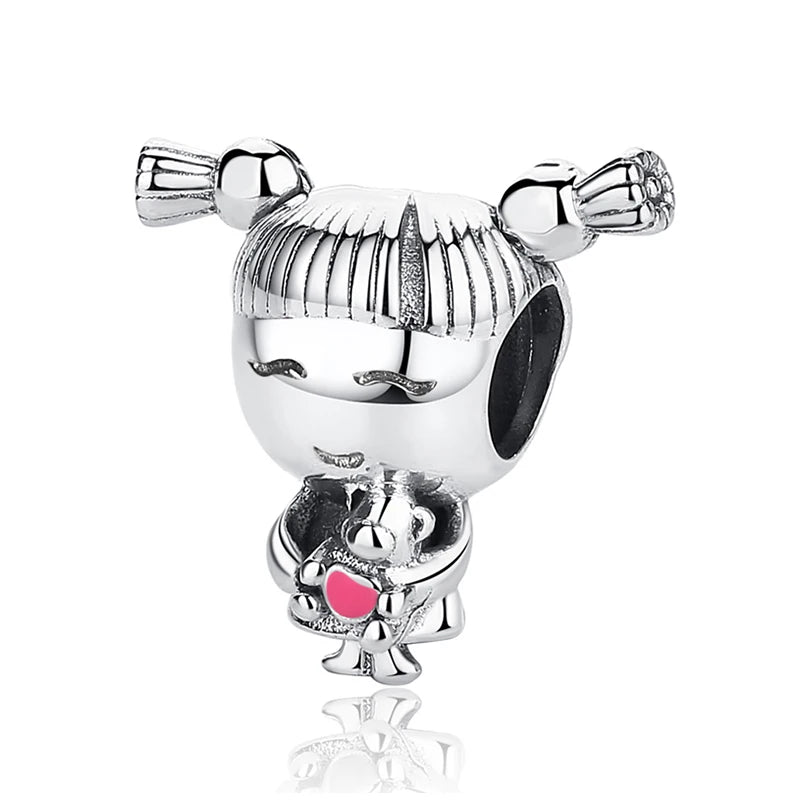 A silver family tree charm jewelry piece featuring a stylized face and a small animal figure.