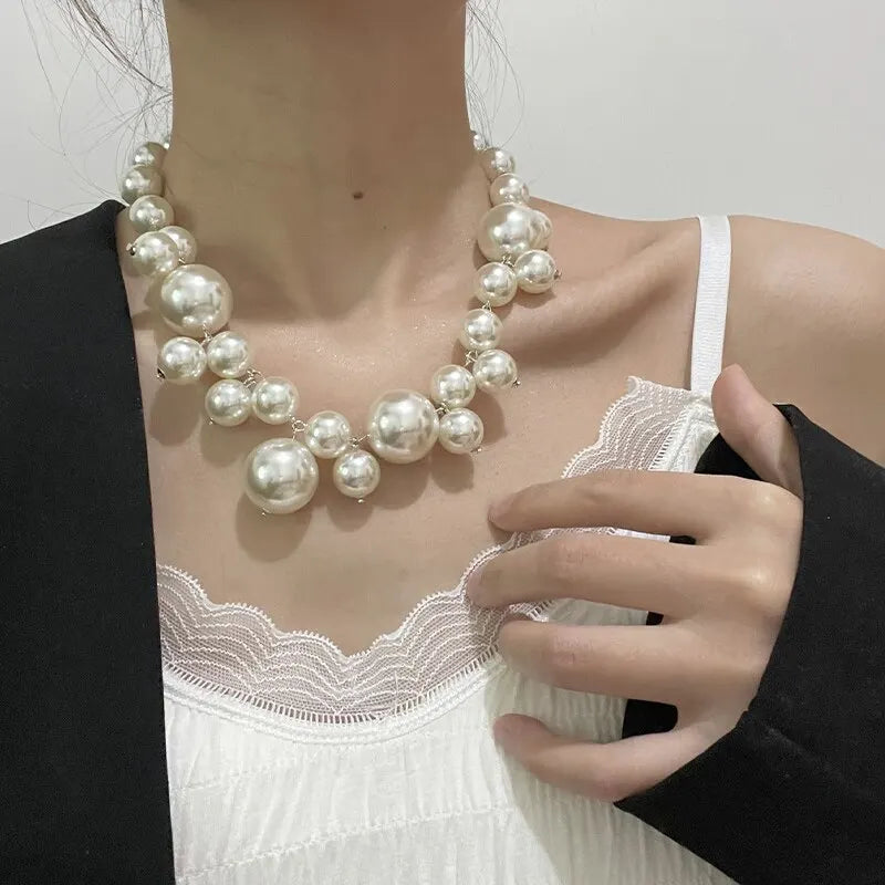 Elegant simulated pearl choker necklace worn around the neck against a white top and black blazer.