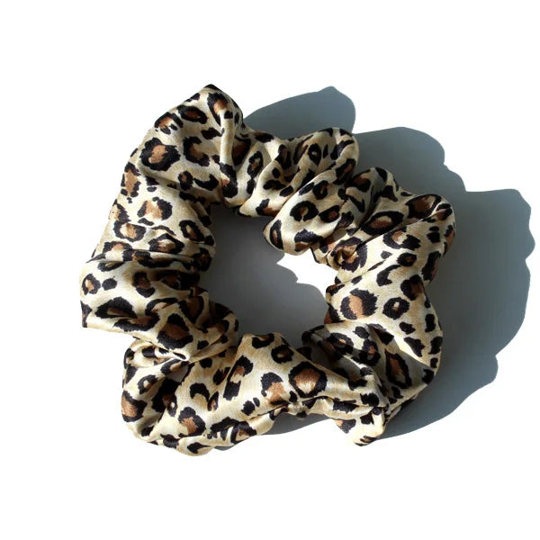 A close-up of luxury pure silk hair scrunchies featuring a leopard print pattern.
