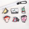A collection of enamel pins featuring whimsical characters and phrases like a yellow bird, a witch, and a pig.