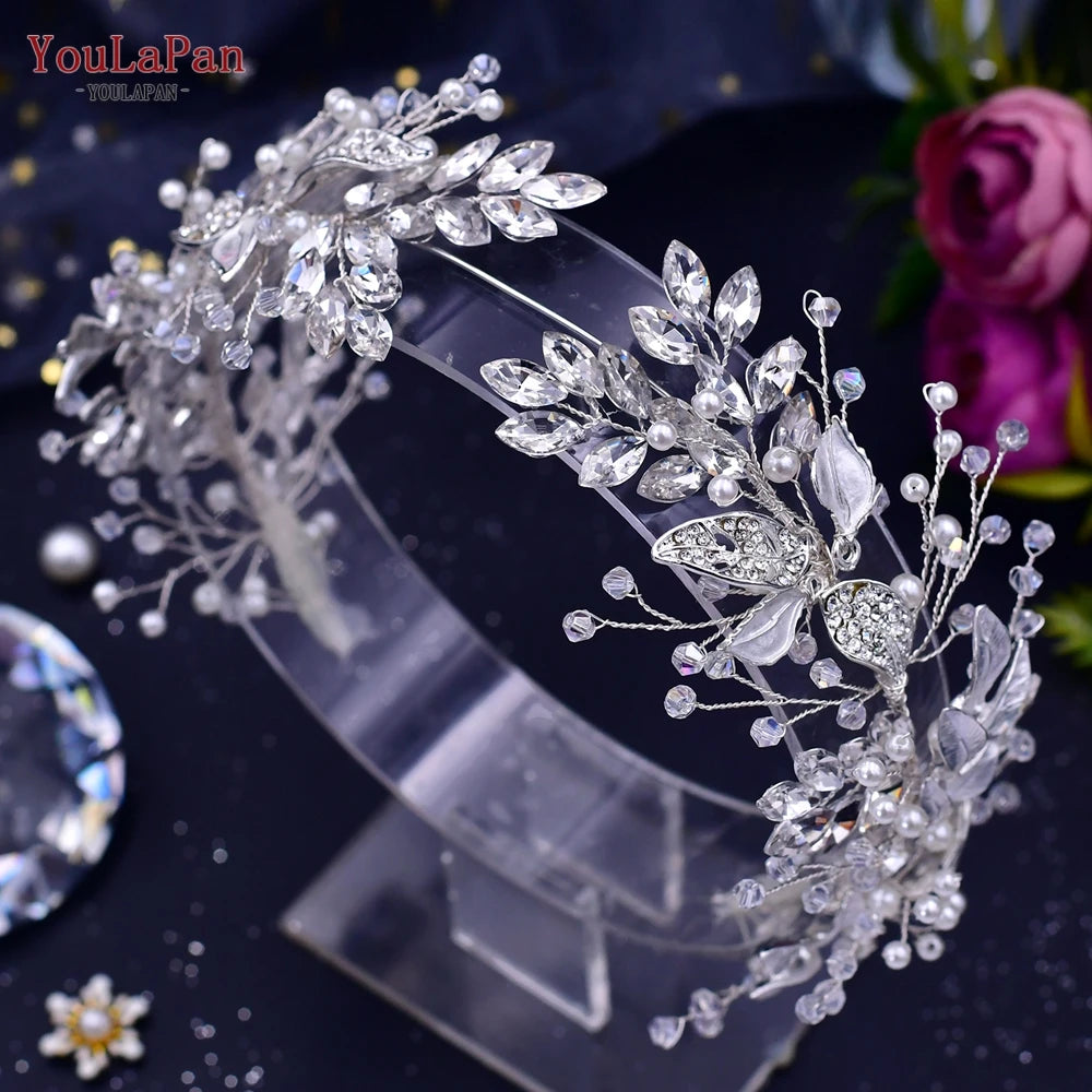 A delicate crystal bridal headband featuring intricate floral and vine designs on a clear stand.