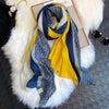 Luxuriöses Baumwoll-Pashmina-Schal mit blau-grau-gelben Streifen und griechischem Muster auf weißem Pelz.