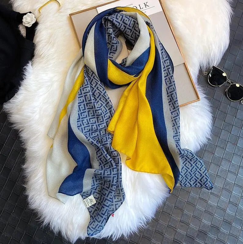 Luxuriöses Baumwoll-Pashmina-Schal mit blau-grau-gelben Streifen und griechischem Muster auf weißem Pelz.