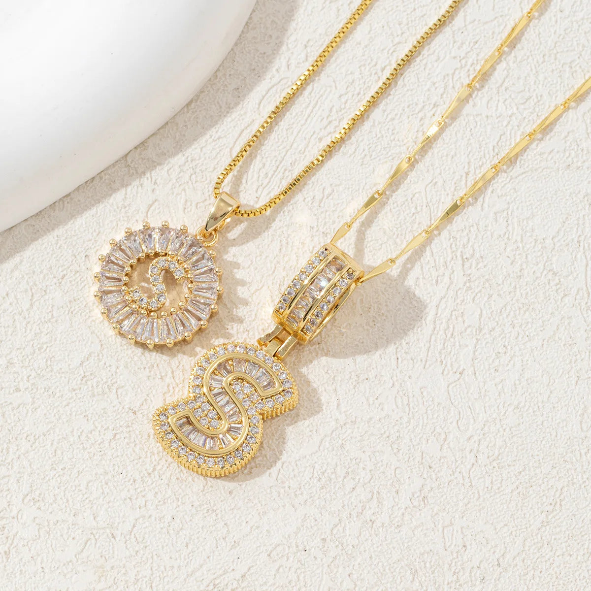 Gold-toned necklace set featuring CZ crystal pendants shaped like the letter S and a circular design.