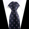 Black silk necktie with a subtle floral paisley pattern and pink accents worn under a white shirt.