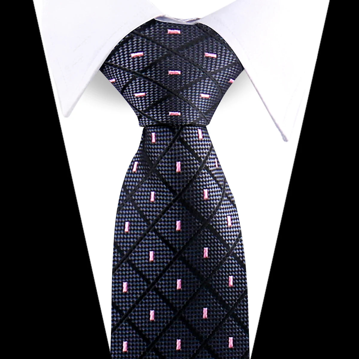 Black silk necktie with a subtle floral paisley pattern and pink accents worn under a white shirt.