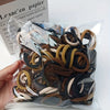A clear plastic bag filled with various brown and black seamless elastic hair ties.