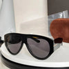 Black oversized pilot sunglasses resting on a white circular stand.