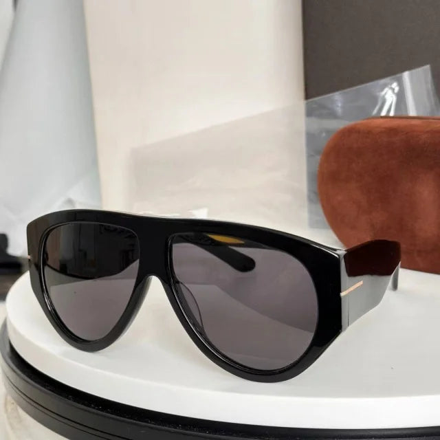Black oversized pilot sunglasses resting on a white circular stand.