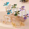 Elegant floral open cuff armlet jewelry featuring blue, green, and purple flowers on gold-toned wire stems