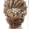A woman's hair styled in an elegant updo with a golden leaf shaped pearl flower hairpin comb.
