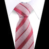 A close-up of an elegant red and white patterned silk necktie tied in a diagonal stripe pattern against a white shirt.
