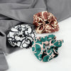 Three colorful knitted hair scrunchie headbands in brown, beige, and green patterns displayed on a gray fabric.