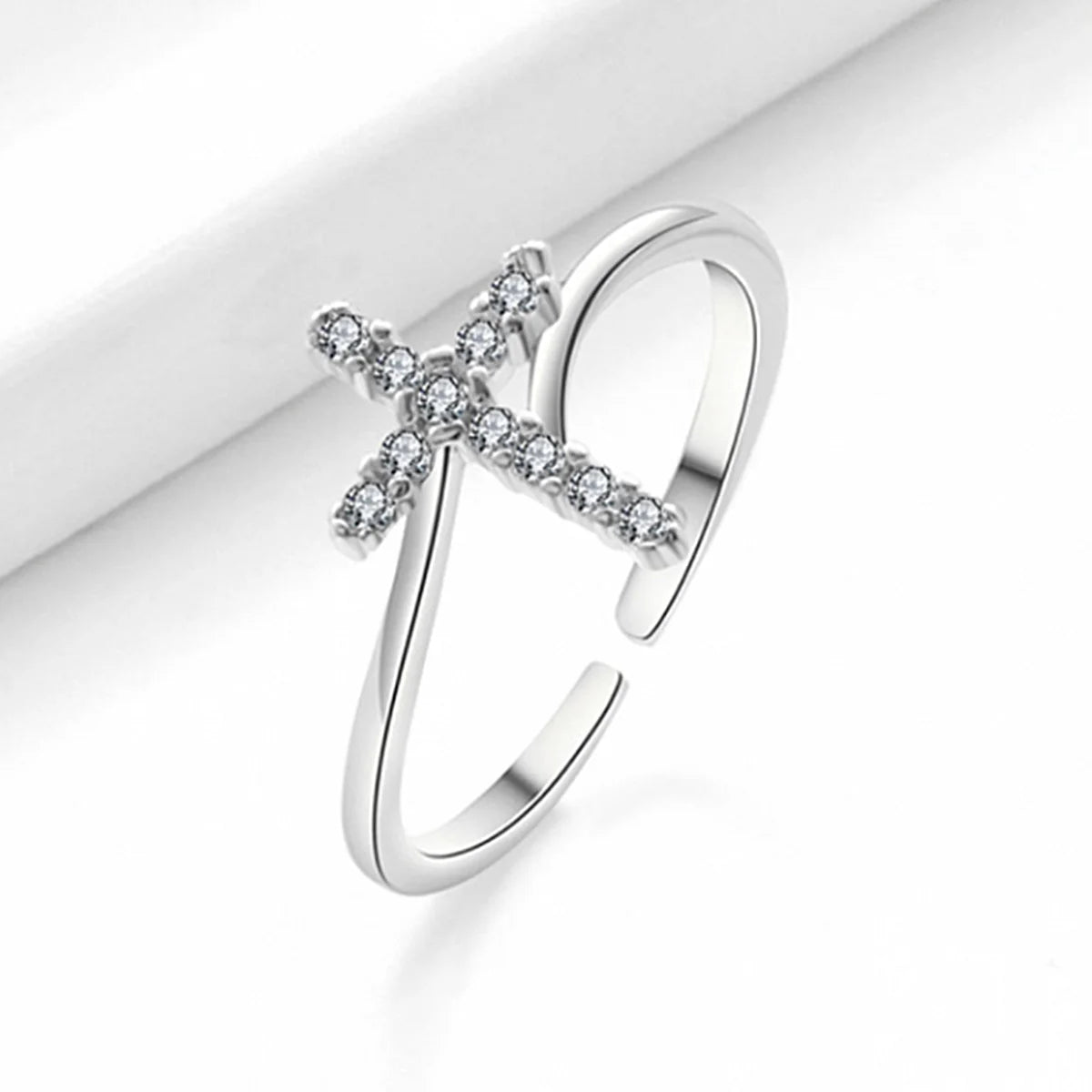 Silberkreuzring und Ohrschmuckset mit Diamantpavé auf weißem Hintergrund