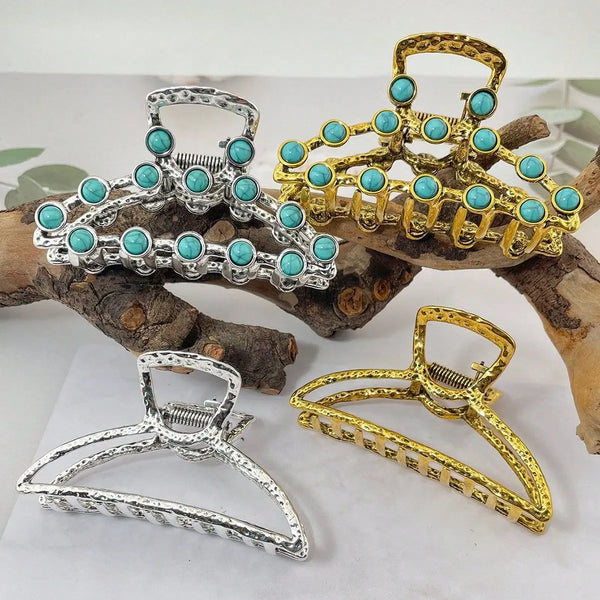 A collection of boho turquoise bead metal hair claw clips in silver and gold tones displayed on wood.