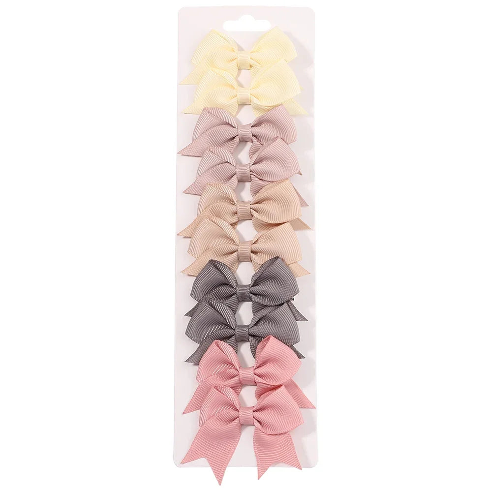 A collection of handmade ribbon bow hair clips in various pastel shades including yellow, pink, beige, and gray.