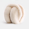 A close-up of classic winter ear muffs made of light beige faux fur.