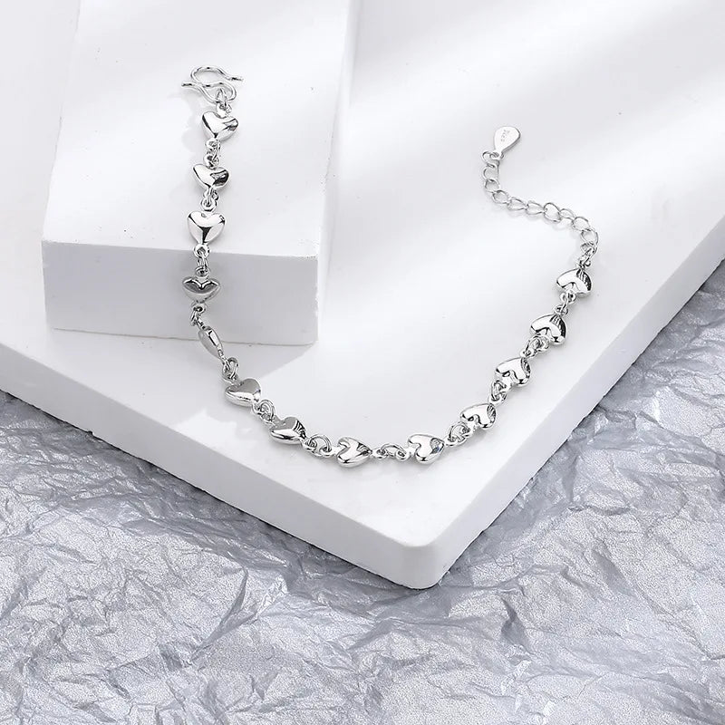 A silver double heart charm bracelet displayed on a white background.