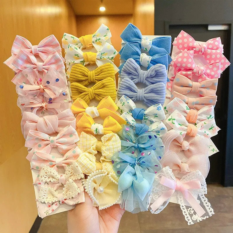 A collection of pink, yellow, and blue flower bow hair ties for girls displayed on a hand.