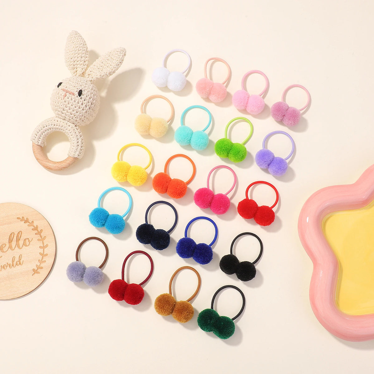 A collection of colorful double plush elastic hair bands and a bunny-shaped teething toy.