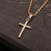 A gold chain necklace with a cross pendant made of sparkling zircon stones resting on a dark surface.