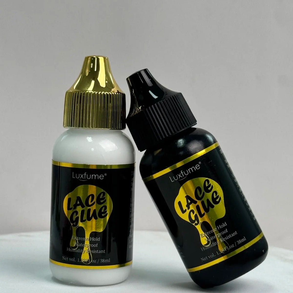 Eine schwarze Flasche Lace Glue Gel neben einer klaren Luxfume-Klebstoffflasche.