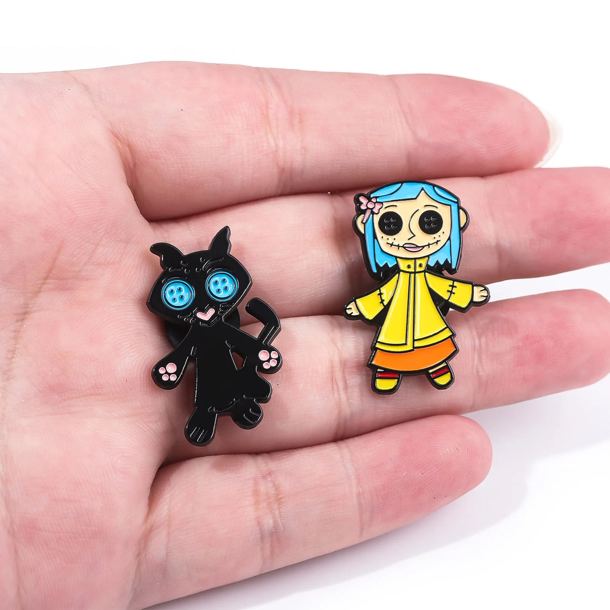 Une paire de pins en émail représentant un chat noir et une fille ressemblant à une sorcière aux cheveux bleus et vêtements j