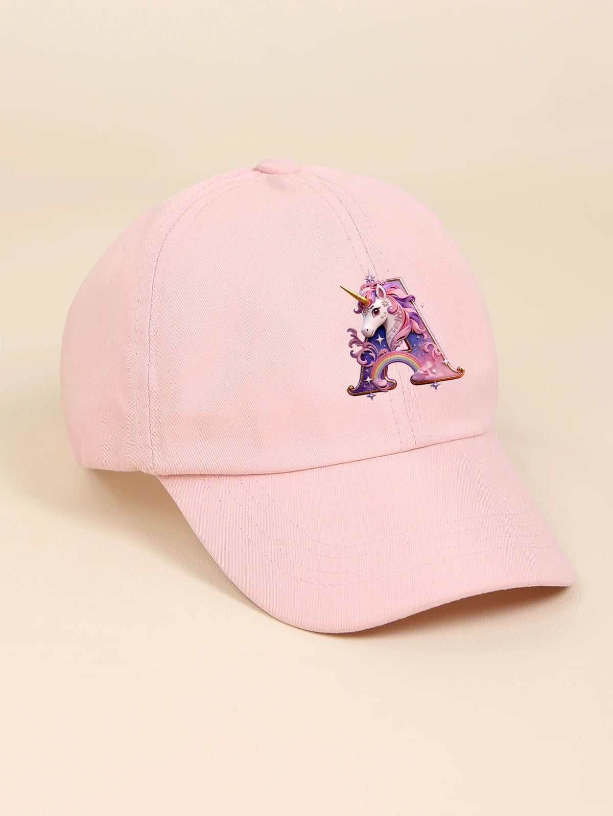 A pink baseball cap featuring a purple and iridescent rainbow unicorn embroidered on the front.