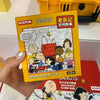 Eine Hand hält eine gelbe Box mit dem Snoopy & Friends Peanut Collectible.