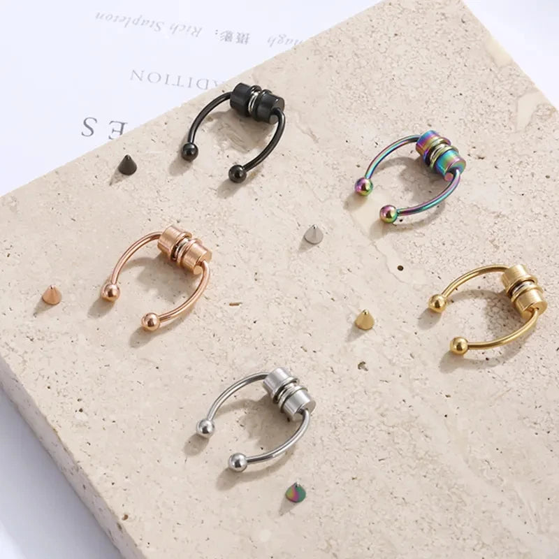 A collection of various hoop and stud nose rings made of gold, silver, and colorful beads displayed on a light surface.