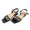 Un par de sandalias de tacón negras adornadas con charms de mariposa de circonita y oro.