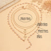 A gold-toned layered necklace featuring pearls and a cross pendant displayed on a neutral background.