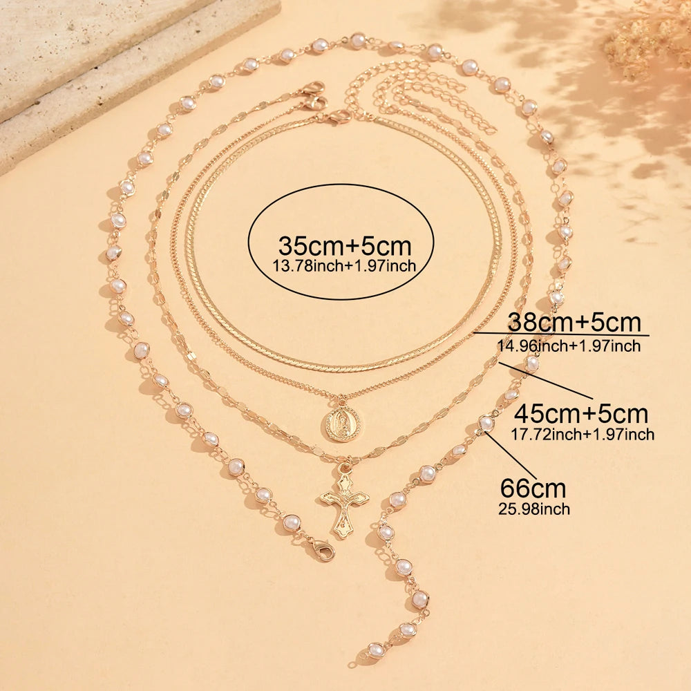 A gold-toned layered necklace featuring pearls and a cross pendant displayed on a neutral background.