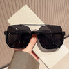 A pair of black double bridge oversized square sunglasses resting on a white surface.