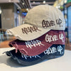 A stack of four vintage washed cotton baseball caps in various colors and styles with embroidered text