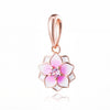 Un delicado colgante de oro rosa con un diseño floral rosa y blanco y un centro de gema transparente.
