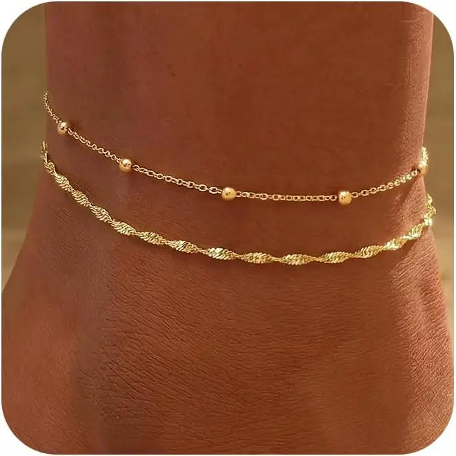 Layered gold-plated twisted ankle bracelets displayed on a person's ankle.