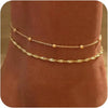 Layered gold-plated twisted ankle bracelets displayed on a person's ankle.