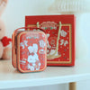 A pink tinplate candy box with a carrying loop featuring a white rabbit design and sweet time text.
