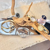 A set of elegant gold and silver watches displayed on a wooden branch next to a glass perfume bottle.