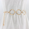 Cinturón de cadena metálica dorada de moda usado sobre un vestido blanco.