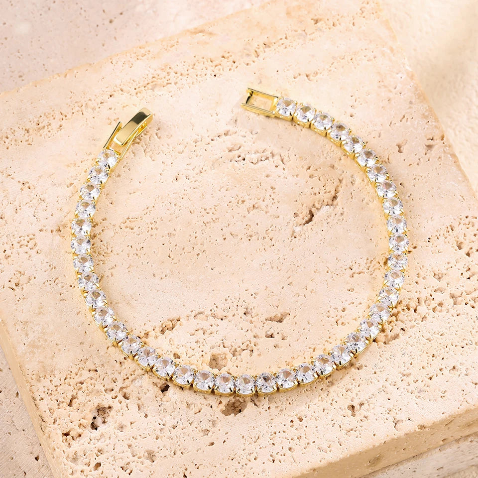 A gold-toned stacking bracelet set featuring a continuous line of clear rhinestones on a light pink stone surface.