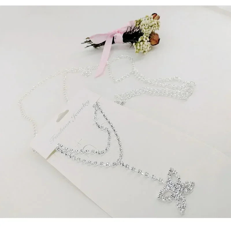A delicate silver crystal diamond waist belt is displayed on a white card with a floral ribbon.