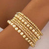 A stack of gold-toned round beaded bracelets worn on a wrist.