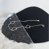 Sterling silver double heart charm bracelet displayed on a black surface next to a piece of rough, translucent stone.